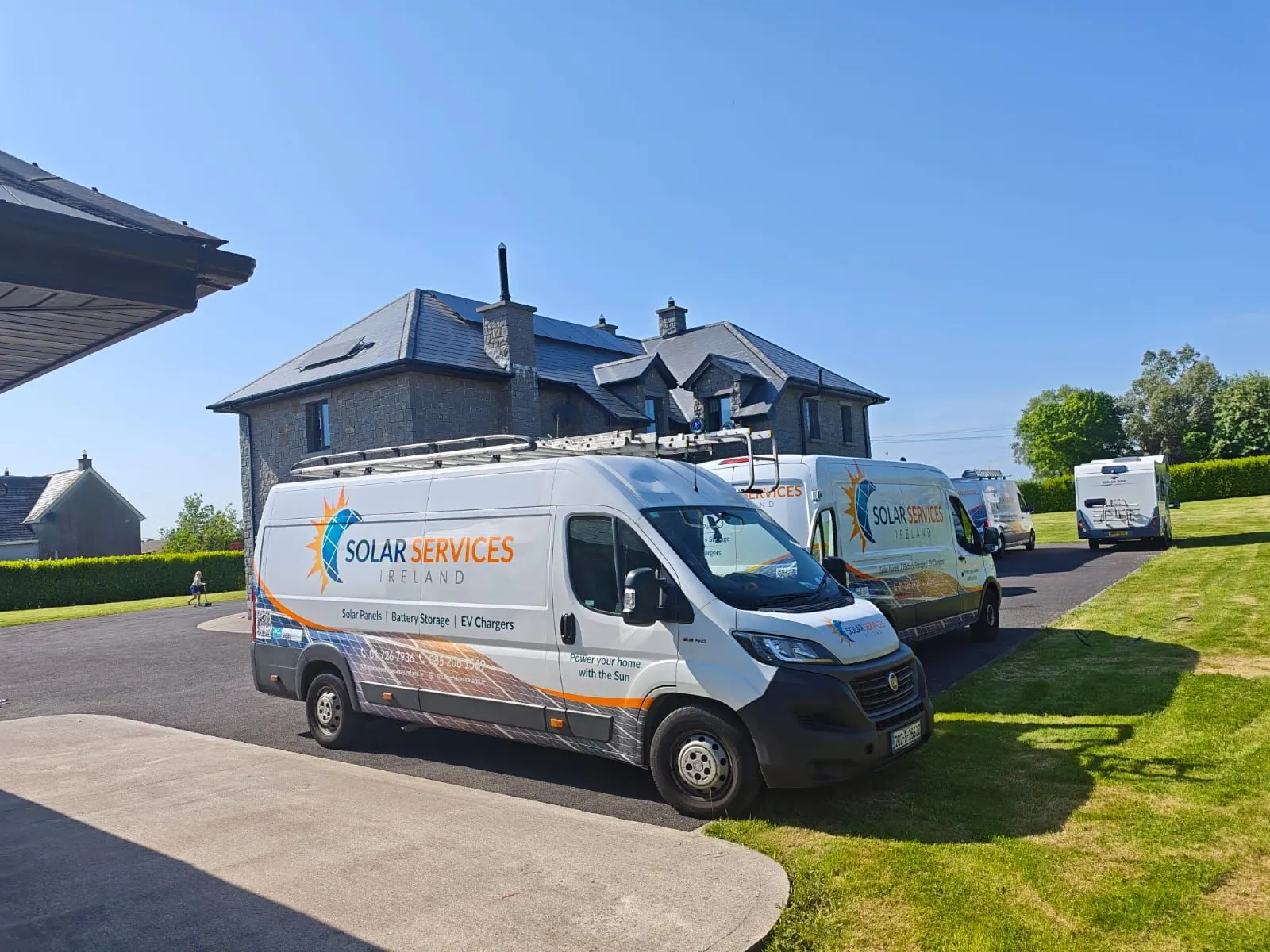Solar Services Ireland vans parked outside a house with solar panels